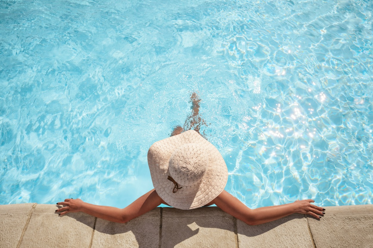woman with sun hat relaxing at pool